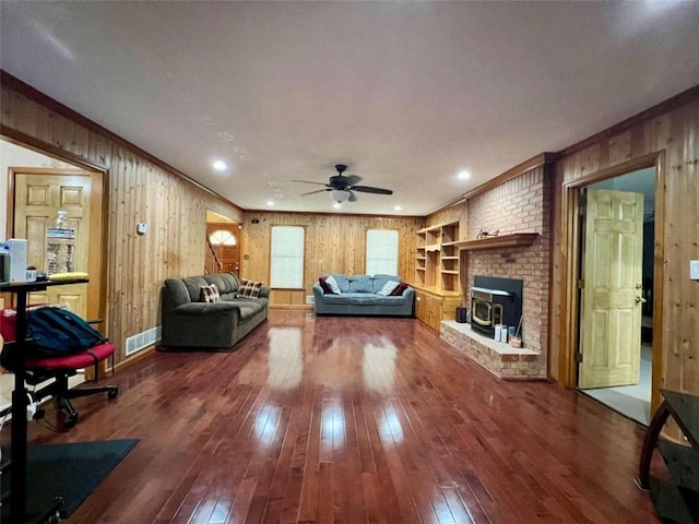 living room with a wood stove, wood-type flooring, and wooden walls