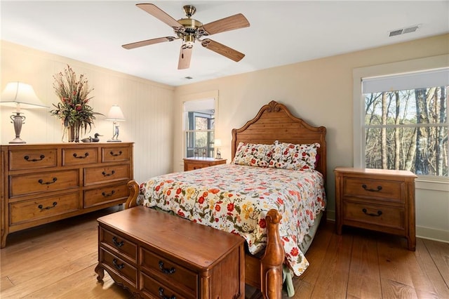 bedroom featuring light wood finished floors, visible vents, and a ceiling fan