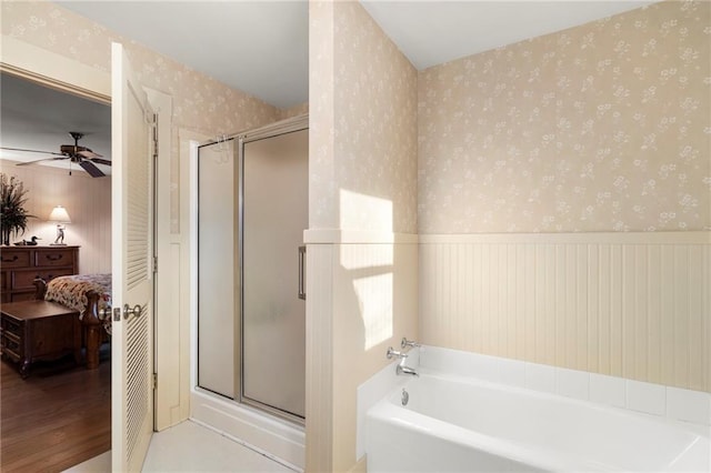 bathroom with a wainscoted wall, a stall shower, ensuite bath, wood finished floors, and wallpapered walls