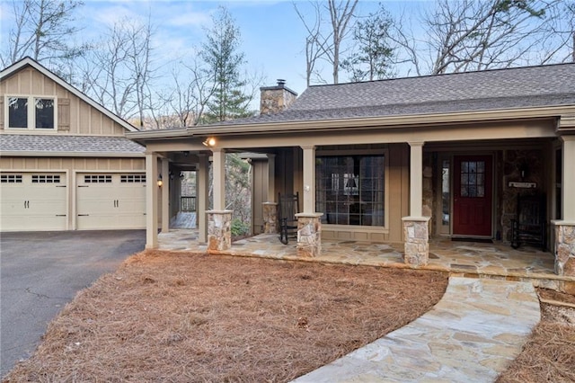 craftsman inspired home with a chimney, aphalt driveway, board and batten siding, and roof with shingles