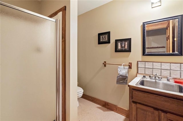 bathroom with toilet, a stall shower, baseboards, and vanity