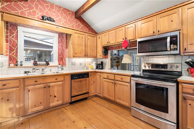 kitchen with a sink, vaulted ceiling with beams, stainless steel appliances, and light countertops