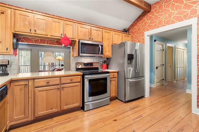 kitchen with light wood finished floors, wallpapered walls, lofted ceiling with beams, appliances with stainless steel finishes, and light countertops