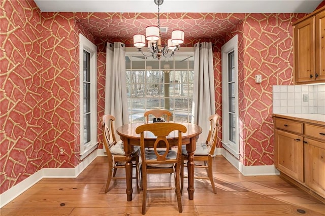 dining area featuring wallpapered walls, baseboards, light wood-style floors, and a notable chandelier