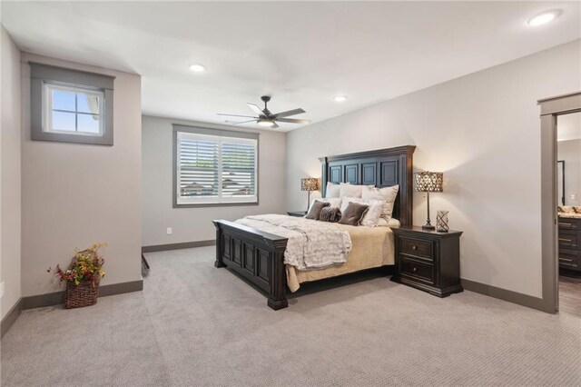 bedroom with light carpet, ensuite bath, and ceiling fan