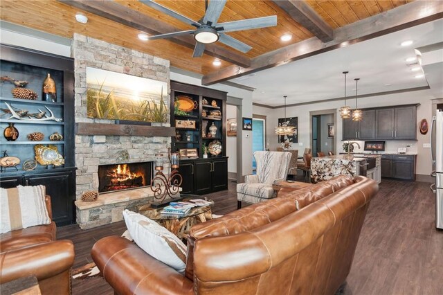 living room featuring ceiling fan, beamed ceiling, dark wood-type flooring, wooden ceiling, and a fireplace