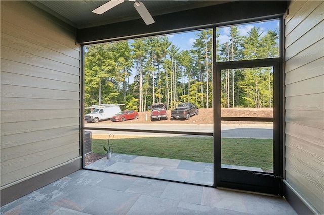 doorway featuring ceiling fan and wood walls