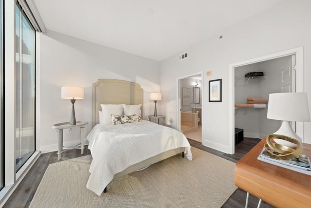 bedroom featuring wood finished floors, visible vents, baseboards, a closet, and a walk in closet