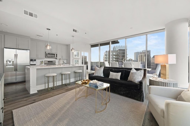 living area with visible vents, a city view, dark wood-style flooring, and expansive windows