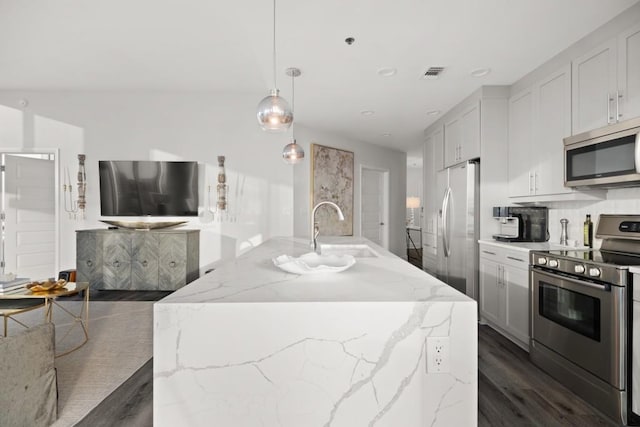 kitchen with visible vents, dark wood-style floors, stainless steel appliances, light stone countertops, and hanging light fixtures