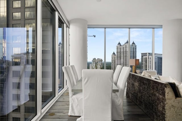 dining space with a city view, wood finished floors, and floor to ceiling windows