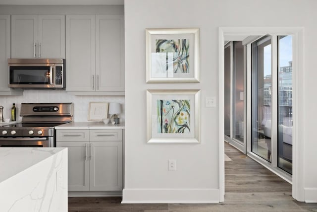 kitchen featuring light stone counters, stainless steel appliances, wood finished floors, and gray cabinets