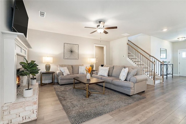 2320 Ridge View Dr, Loganville, GA 30052 - living area with a warm lit fireplace, stairs, a ceiling fan, light wood finished floors, and baseboards