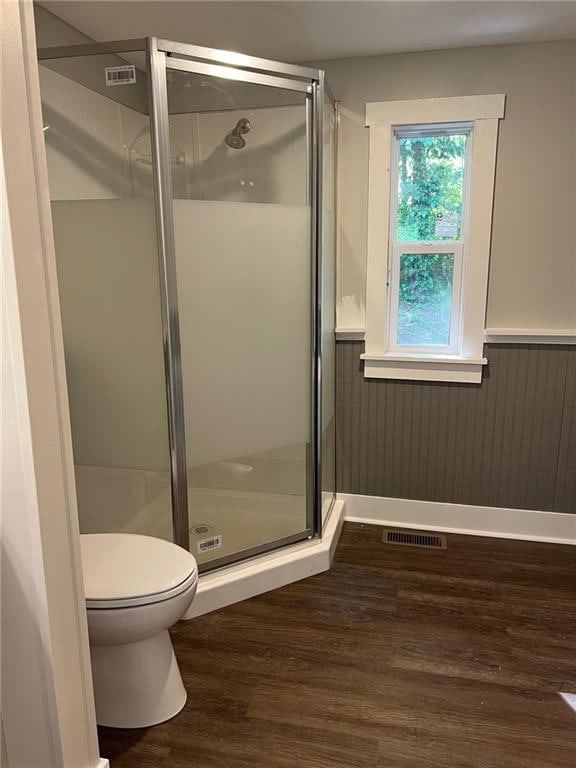 bathroom featuring toilet, hardwood / wood-style flooring, and a shower with shower door