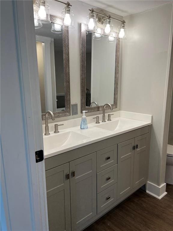 bathroom with double vanity, hardwood / wood-style floors, and toilet