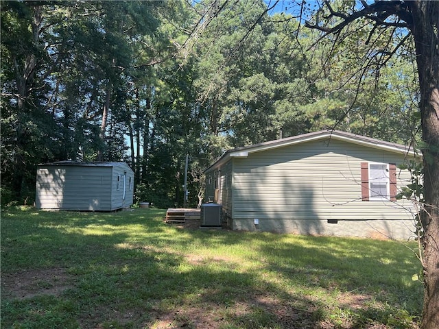 view of side of property with a yard, central AC unit, and a storage shed