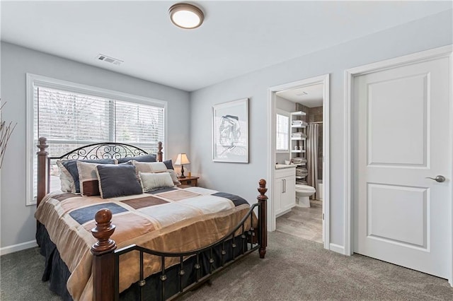 carpeted bedroom with visible vents, baseboards, and ensuite bathroom