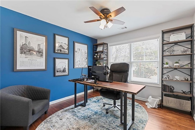 office area featuring a ceiling fan, baseboards, visible vents, and wood finished floors