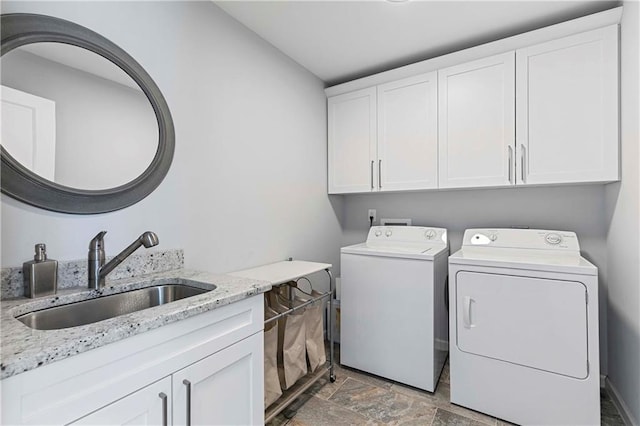 washroom with washing machine and dryer, stone finish floor, a sink, and cabinet space