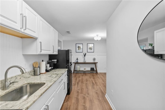 kitchen featuring light wood-style floors, visible vents, white cabinetry, and a sink