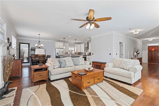 living area featuring dark wood-style flooring, crown molding, and ceiling fan with notable chandelier