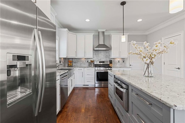 kitchen with appliances with stainless steel finishes, ornamental molding, dark wood-style flooring, wall chimney range hood, and a sink