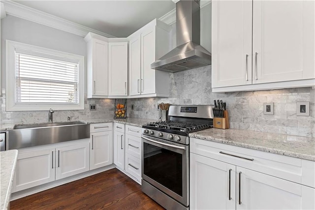 kitchen featuring white cabinets, dark wood-type flooring, stainless steel gas range, wall chimney range hood, and a sink