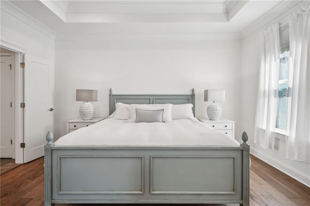 bedroom with a tray ceiling, baseboards, dark wood-type flooring, and ornamental molding