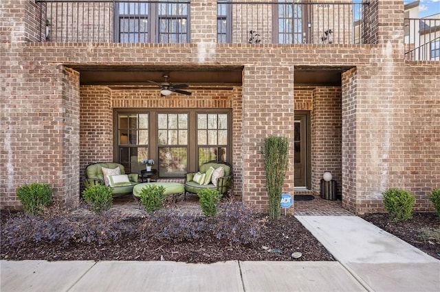 view of exterior entry with an outdoor hangout area, brick siding, and ceiling fan