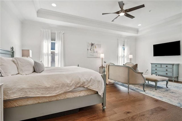 bedroom with recessed lighting, a raised ceiling, ornamental molding, and dark wood-style flooring