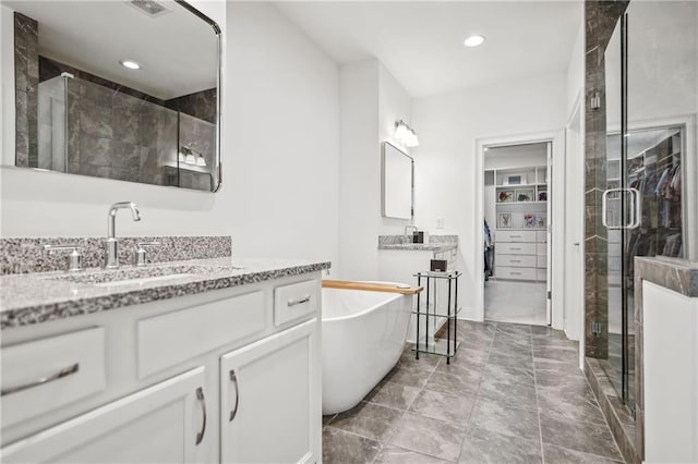 full bath featuring a stall shower, a sink, recessed lighting, a freestanding bath, and a spacious closet