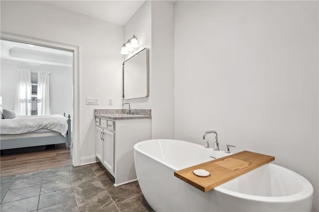 bathroom with vanity, ensuite bath, a freestanding tub, and baseboards