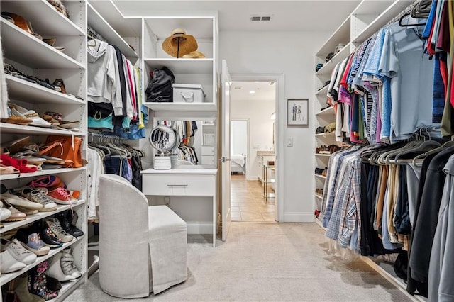 spacious closet with light tile patterned floors, visible vents, and light colored carpet