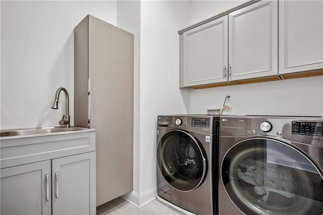 clothes washing area featuring baseboards, light tile patterned floors, washer and dryer, cabinet space, and a sink