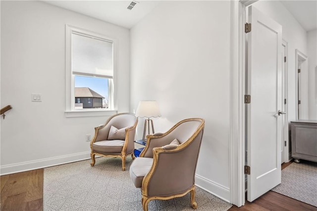 living area featuring visible vents, baseboards, and wood finished floors