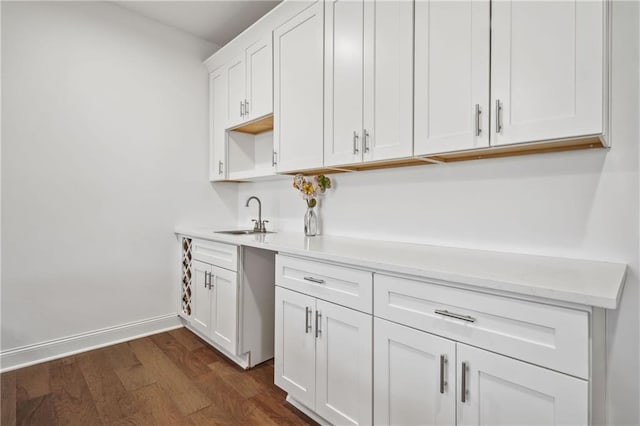 kitchen with a sink, baseboards, dark wood-style floors, and white cabinetry