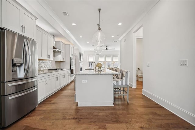 kitchen with a kitchen island with sink, decorative backsplash, dark wood-type flooring, appliances with stainless steel finishes, and a kitchen breakfast bar