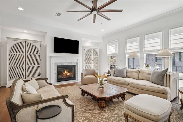 living area with a ceiling fan, wood finished floors, visible vents, recessed lighting, and a fireplace