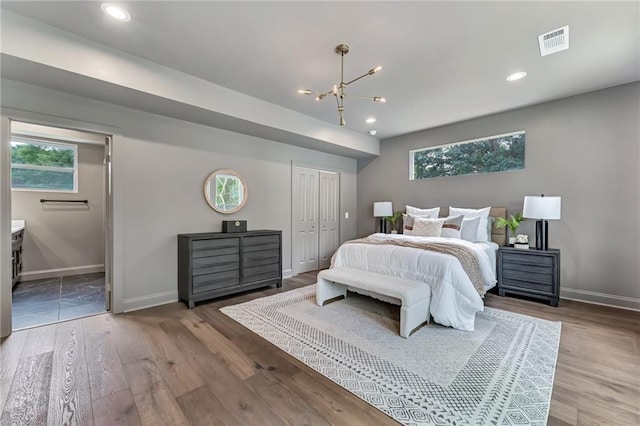 bedroom with hardwood / wood-style flooring, an inviting chandelier, and a closet