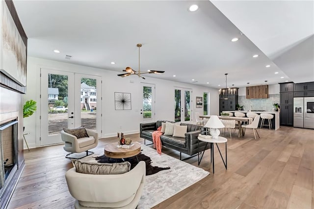 living room with french doors, a chandelier, and light wood-type flooring