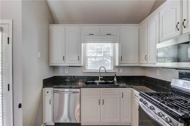926 Masters Dr, Monroe, GA 30655 - kitchen featuring appliances with stainless steel finishes, white cabinets, a textured ceiling, dark stone countertops, and vaulted ceiling