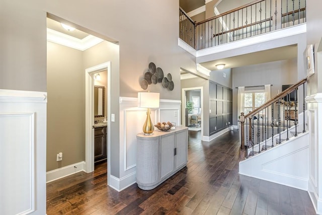 entryway with crown molding, a towering ceiling, and dark wood-type flooring