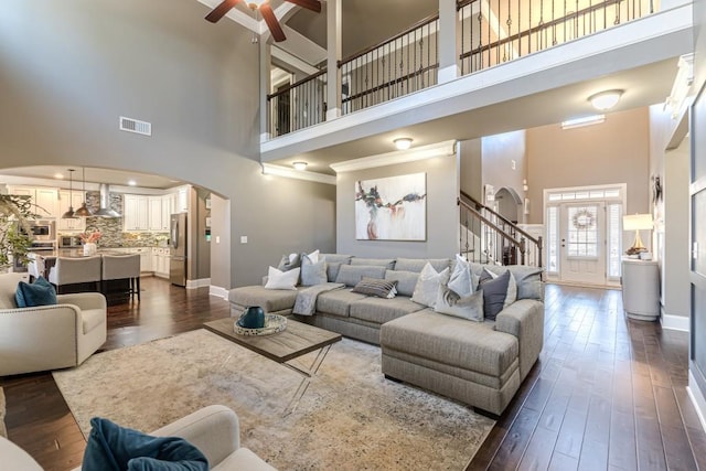 living room featuring ceiling fan, a towering ceiling, and dark hardwood / wood-style floors