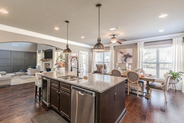 kitchen featuring dark wood-type flooring, a center island with sink, sink, stainless steel dishwasher, and dark brown cabinetry