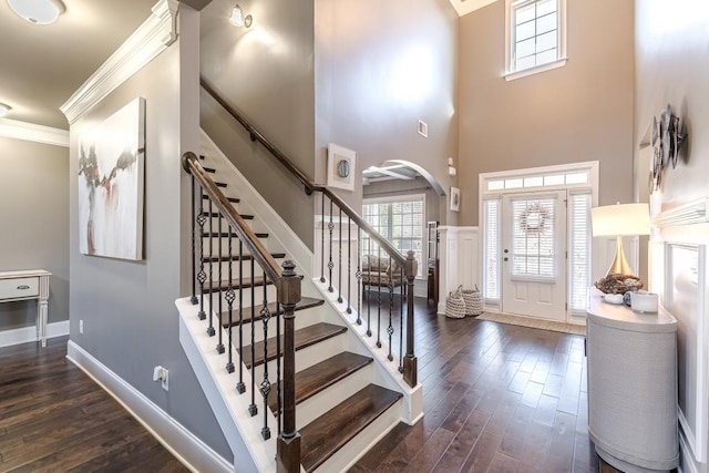 entrance foyer featuring dark hardwood / wood-style flooring, a towering ceiling, and crown molding