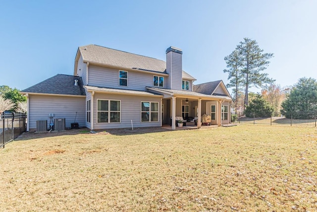 rear view of property featuring a yard, central AC unit, and a patio area