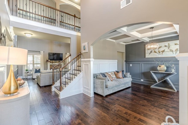 living room featuring beamed ceiling, dark hardwood / wood-style floors, a towering ceiling, and coffered ceiling