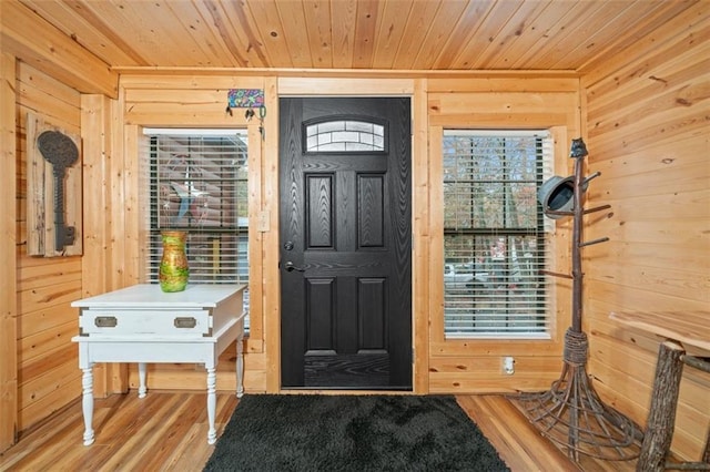 foyer entrance with wood walls, hardwood / wood-style floors, and wood ceiling