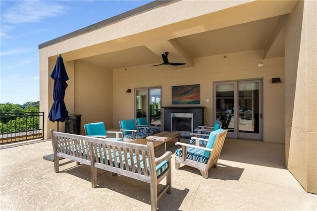 view of patio featuring an outdoor living space with a fireplace and a ceiling fan
