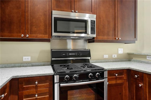 kitchen featuring stainless steel appliances and light stone counters